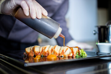 closeup chef preparing salad with eel cucumbers and lettuce leaves on mat