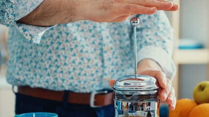 Senior man preparing coffee using french press in kitchen for breakfast. Elderly person in the morning enjoying fresh brown cafe espresso cup caffeine from vintage mug, filter relax refreshment