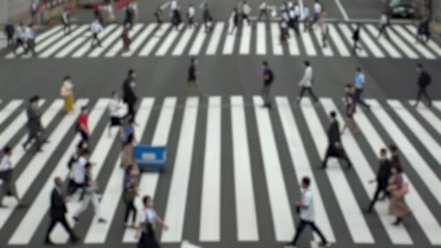 TOKYO, JAPAN : Aerial high angle view of crowd of people walking at zebra crossing in rush hour. Commuters at the street. Japanese city life style, business and work concept. Slow motion blurred shot.