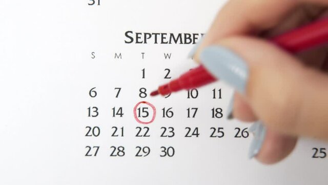 Female hand circle day in calendar date with a red marker. Business Basics Wall Calendar Planner and Organizer. September 15th