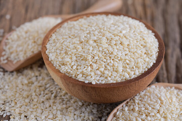 White sesame in a wooden bowl on a wooden background, close-up.