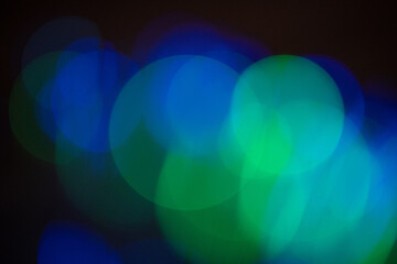 Green and blue light bokeh in black background. Copy space.