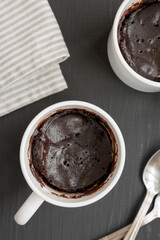 Homemade Brownie in a Mug on a black surface, top view. Overhead, from above, flat lay.