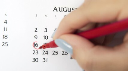 Female hand circle day in calendar date with a red marker. Business Basics Wall Calendar Planner and Organizer. August 16th