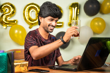 Young man partying during new year or Christmas celebration video call on laptop - concept of distant holyday celebration due to coronavirus or covid-19 pandemic.