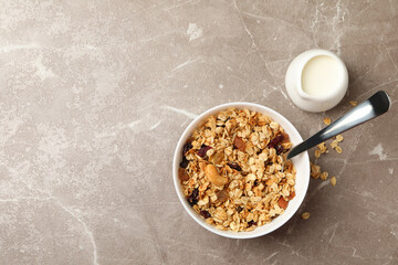 Bowl with granola and milk on gray background