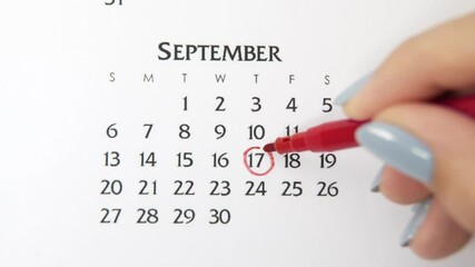 Female hand circle day in calendar date with a red marker. Business Basics Wall Calendar Planner and Organizer. September 17th