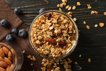 Glass jar with tasty granola on wooden background