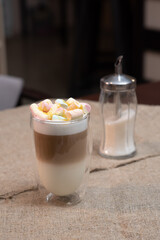 Delicious freshly made coffee latte with marshmallows stands on the table