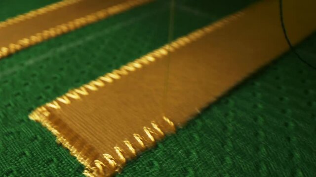 Machine tool embroiders golden element on hockey uniform