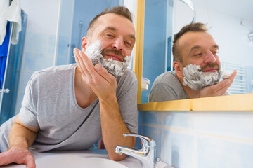 Guy shaving his beard in bathroom