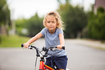 The little girl rides a bike in the city