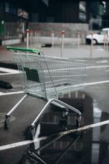 a supermarket basket is on the asvalt and a puddle of water, a wheelchair