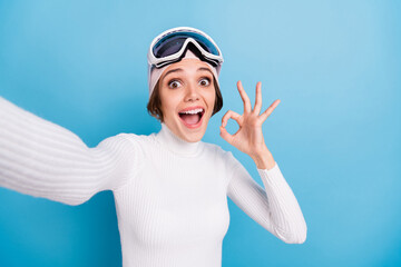 Photo of nice shocked brunette girl wear white turlteneck hat make ok sign take selfie isolated on blue color background