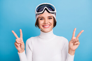 Photo of positive attractive woman show two v-sign greeting symbol skier isolated on pastel blue color background