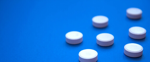 Set of white pills on blue background. Pills background. White tablets on a blue background