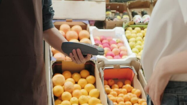 Handheld mid-section of unrecognizable young woman using debit card to pay for groceries at market
