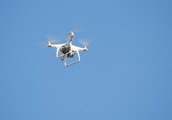 Fototapeta na wymiar White flying drone against the blue sky