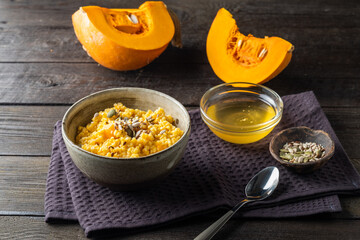 Cooking healthy porridge with pumpkin, honey, seeds Rustic table with healthy breakfast.