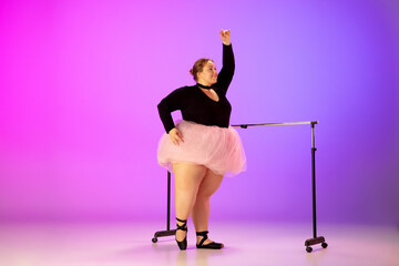 Graceful. Beautiful caucasian plus size model practicing ballet dance on gradient purple-pink studio background in neon light. Concept of motivation, inclusion, dreams and achievements.