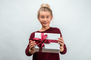 Portrait of happy blonde girl holding gift decorated with ribbon. Studio shot white background