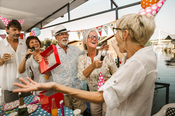 Senior people celebrating birthday in the cottage on the river singing karaoke.