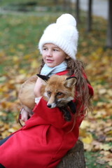 Girl holding fox in her arms in autumn park