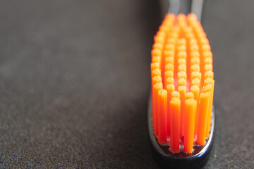 Black head toothbrush with orange bristles close up