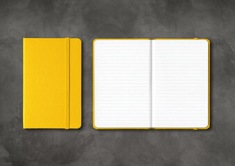 Yellow closed and open lined notebooks on dark concrete background