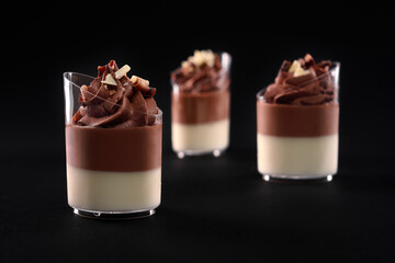 Glasses with layered chocolate panna cotta isolated on black.