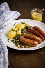 Oldenburger Grünkohl mit Pinkel, Kohlwurst, Senf und Kartoffeln auf Holz Tisch