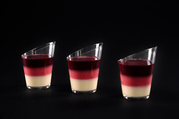 Jelly layered dessert in three glasses isolated on black.
