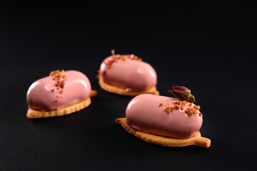 Pink cakes with glazed smooth surface isolated on black.