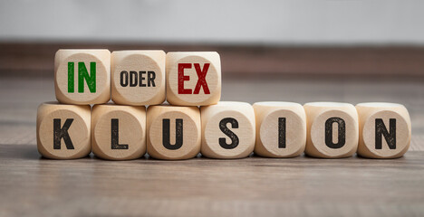 Cubes, dice or blocks with the german words for inclusion and exclusion - inklusion exklusion on wooden background