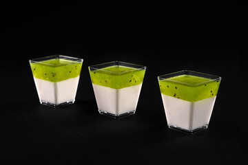 Three small glasses with panna cotta isolated on black.