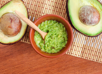 Fresh avocado puree in a small clay bowl. Guacamole, homemade face mask, natural beauty treatment and spa recipe. Top view, copy space.