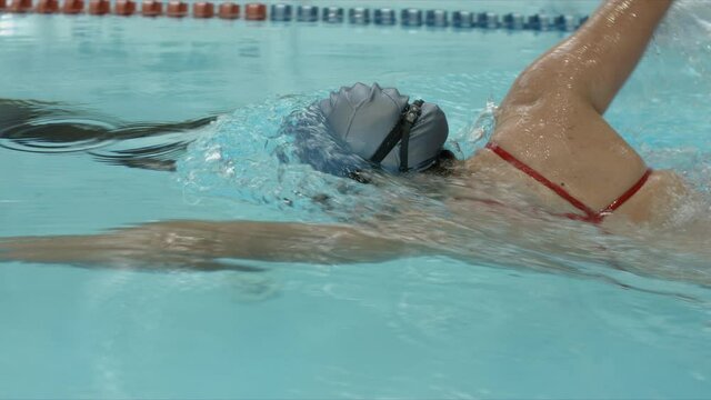 Young professional swimmer training front crawl technique for swimming competition and do flip turn. Slow motion video. 