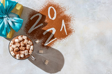 Cup of hot cocoa with marshmallows and numbers 2021 from cocoa powder. The concept of cosy holidays and New Year.
