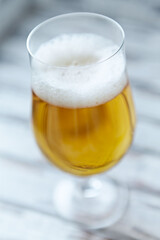  Glass of beer on bright wooden background. Close up.