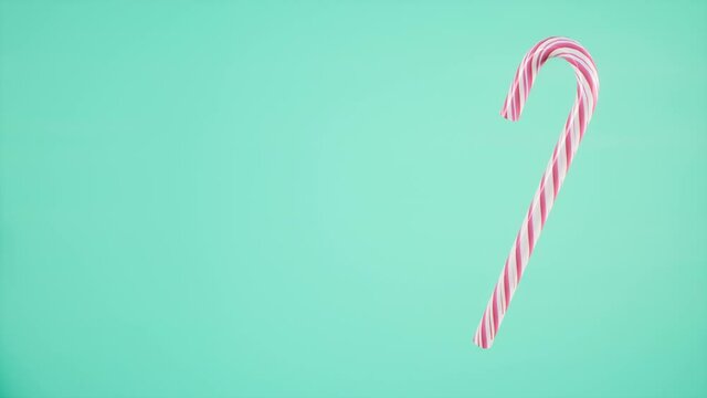 candy cane rotating on mint green background, loop video christmas concept