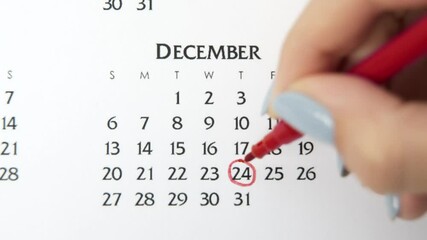Female hand circle day in calendar date with a red marker. Business Basics Wall Calendar Planner and Organizer. December 24th