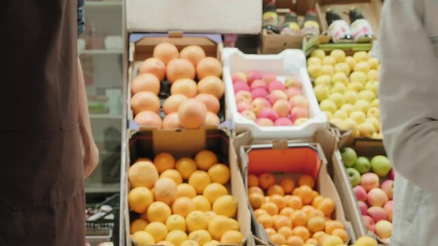 Handheld mid-section shot of unrecognizable couple using mobile phone to pay for groceries at market
