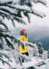 Happy girl in a yellow jacket throwing snow in the mountains and is happy. Adventure and travel concept. Celebration Holidays
