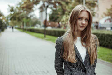 Confident girl with long blonde hairl wearing grey coat