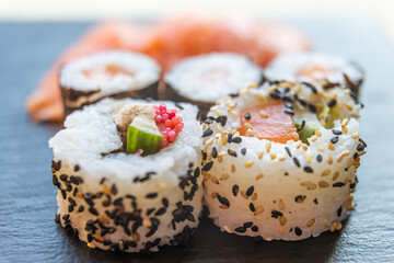 Sushi, uramaki, rolls and sashimi on a slate tray.