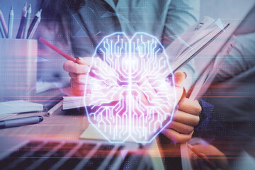 Double exposure of woman's writing hand on background with brain hud. Concept of learning.