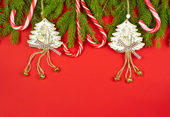Christmas concept. Christmas decorations and candy canes on fir branches over red background