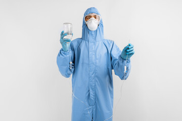 Doctor in a protective medical suit, mask, glasses and gloves, prepares a dropper for installation, on a white background, medical care concept, coronavirus