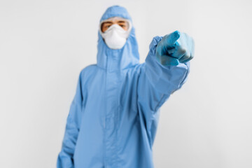 Fototapeta na wymiar male doctor dressed in a protective suit against coronavirus, wearing a medical mask, glasses and gloves, with his arms crossed on an white background. Quarantine, coronavirus