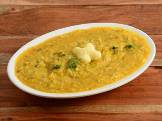 Dal khichdi or Khichadi, Tasty Indian recipe served in bowl over rustic wooden background, The food made of dal and rice combined with whole spices, onions, garlic and tomatoes etc. Selective focus